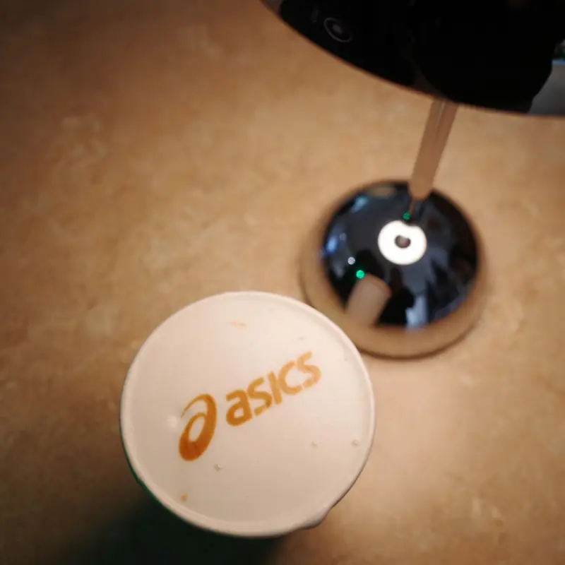 The ASICS logo printed on the foam of an iced drink