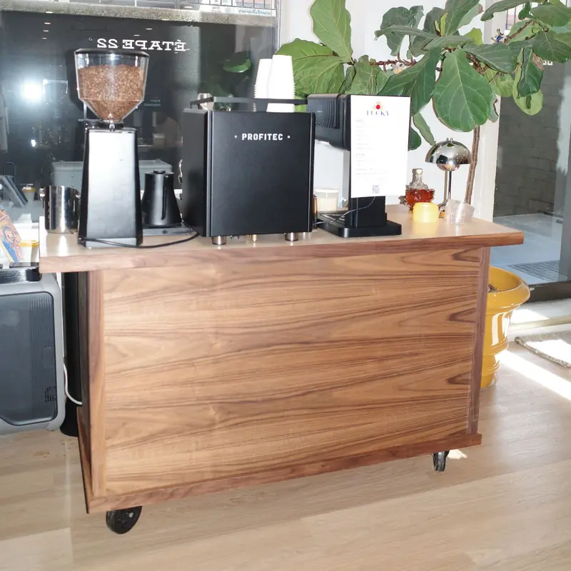 Lucky Coffee's walnut espresso cart set up inside a bright event space