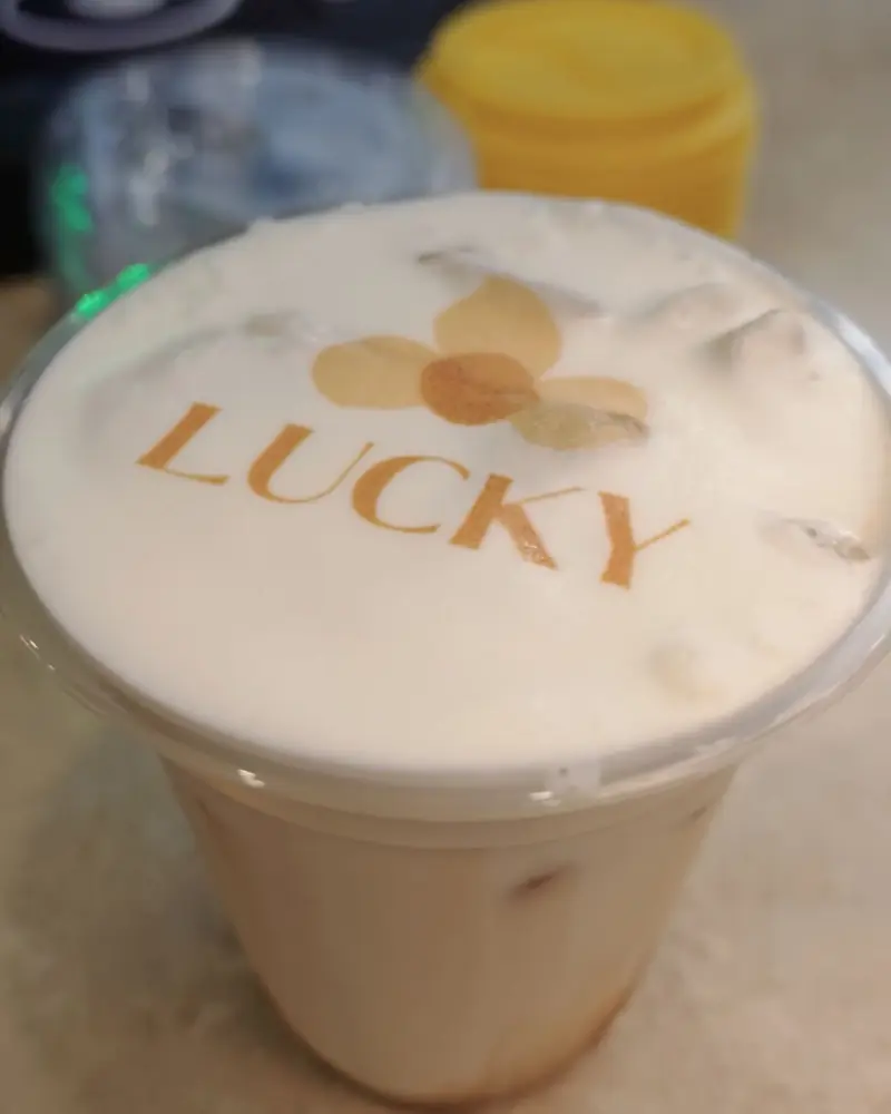 A Lucky Coffee logo printed on latte foam, showing the printing detail