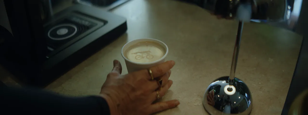 Lucky Coffee commercial: espresso preparation, milk pouring, latte art printing and a finished drink beside the chrome lamp